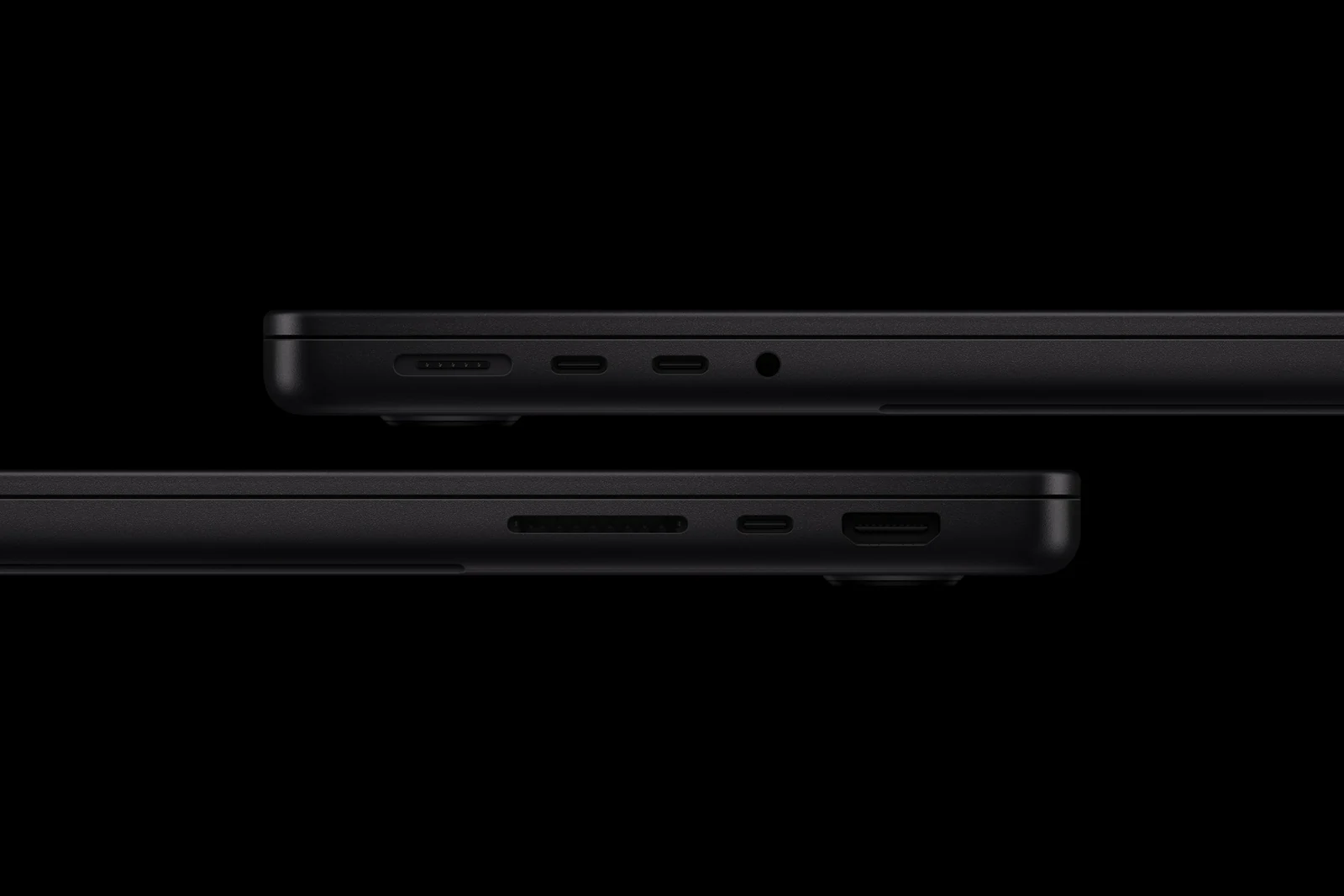 Dva černé MacBooky Pro z boku nad sebou: vlevo port MagSafe, dva USB-C a sluchátkový konektor, vpravo slot na SD karty, třetí USB-C a HDMI