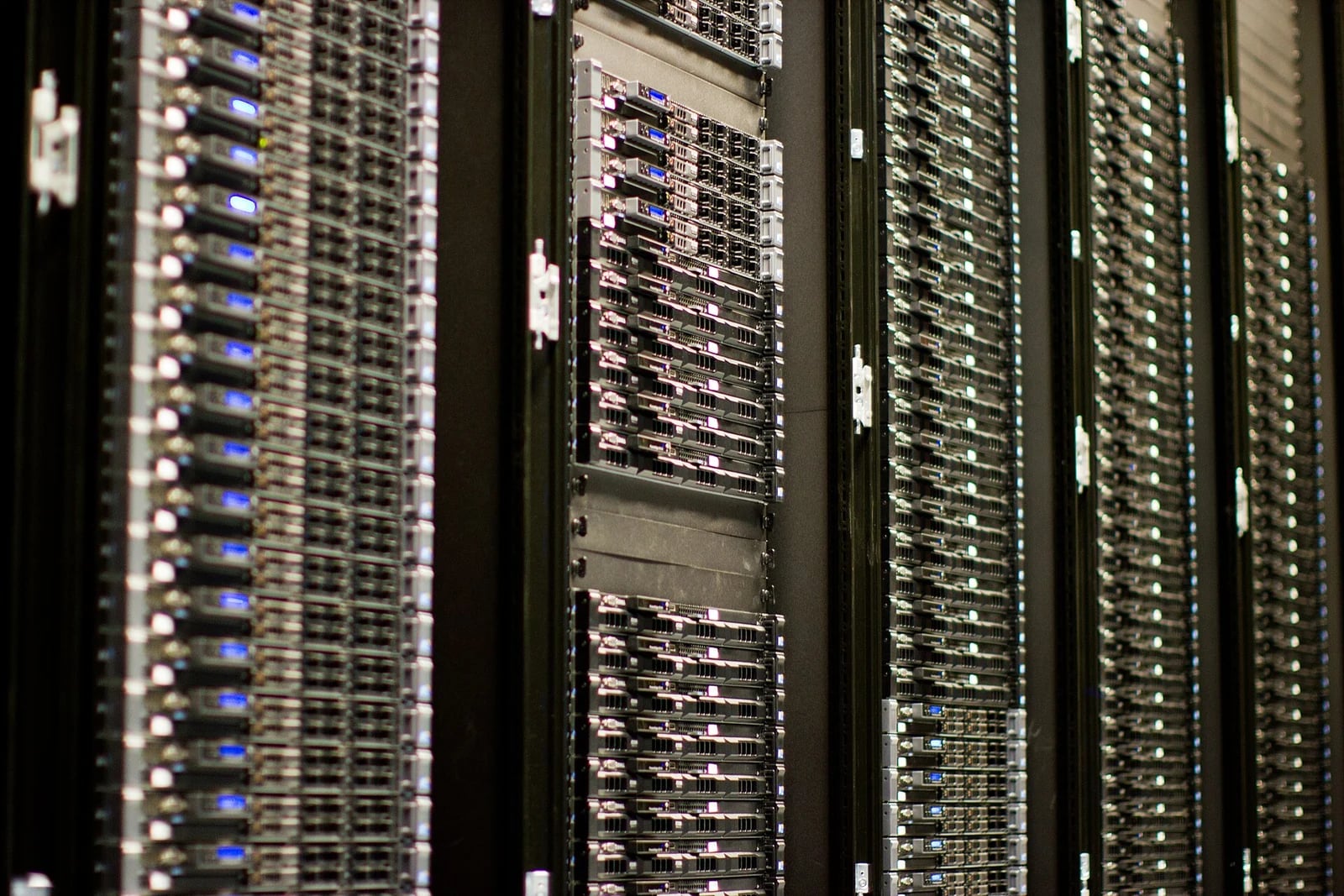 Řady serverových racků v datovém centru, desítky serverů nad sebou s modrými a bílými kontrolkami